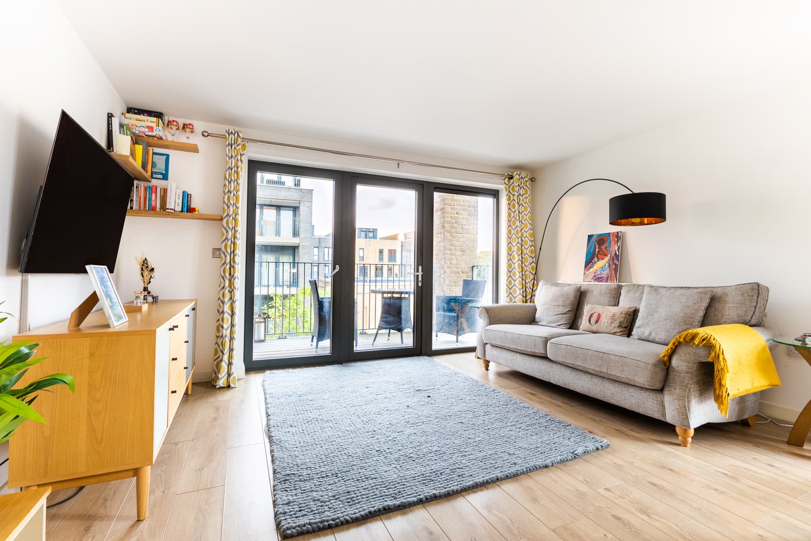 Bright, open-plan living room with a balcony in an apartment we operate